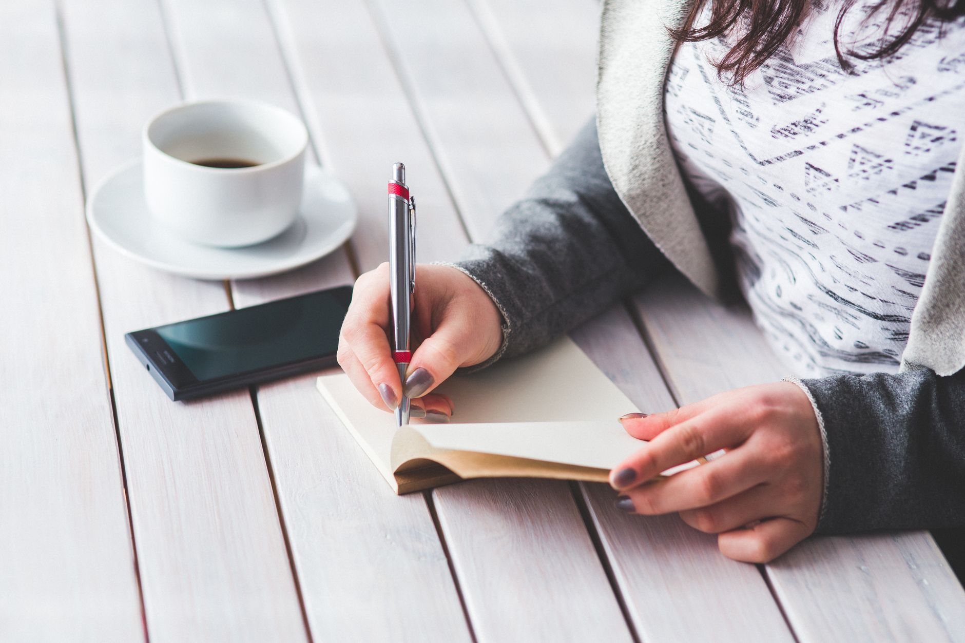 コーヒーを飲みながらノートに考えを書き出す様子